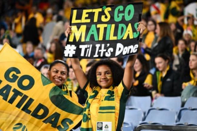 A young Matildas fan holding a sign in the stands at Stadium Australia